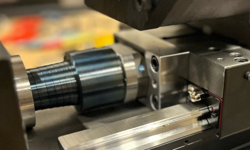 Närbild av en svarv för metallbearbetning, som visar skärverktyget och ett cylindriskt arbetsstycke som bearbetas med exakta enheter för noggranna mätningar.